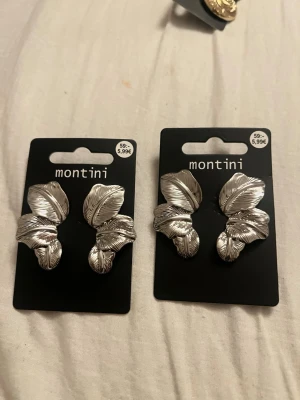 Silvriga bladformade örhängen Montini - Säljer ett par silvriga örhängen från Montini med snygg bladformad design. Örhängena har en blank metallisk finish och är perfekta för dig som gillar statement-accessoarer. Säljs i originalförpackning. Säljer 1 för 59kr och 2 för 120kr