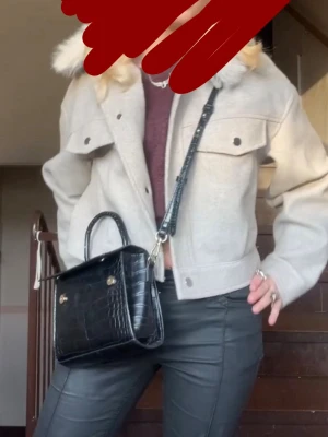 Beige jacka från Bershka - Snygg beige jacka från Bershka med croppad passform och stor krage i fuskpäls. Jackan har två bröstfickor med knappar, långa ärmar och stängs med tryckknappar framtill.