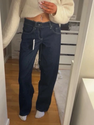 Mörkblå wide leg jeans - Snygga mörkblå jeans med wide leg passform och hög midja. Klassisk femficksmodell med kontrastsömmar och raka ben. Jeansen är tillverkade i kraftig denim och har en tidlös look som passar till allt. Från subdued storlek 38 men är små så passar 32/34. Nya med prislapp, köpta för 800