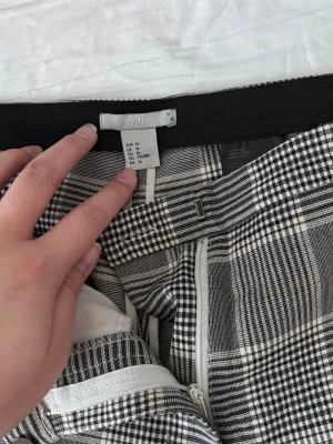 Rutiga kostymbyxor från H&M - Snygga kostymbyxor från H&M i svart sopplad rutigt mönster. 2 fickor. 