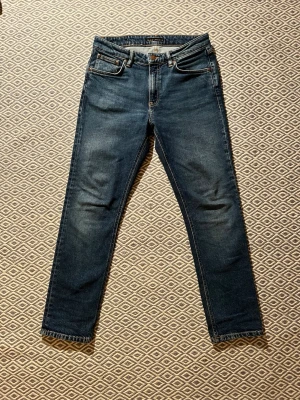 Blå Nudie Jeans - Riktigt feta blå slim fit nudies med lätt tvättade detaljer. Knappt använda och inga defekter. Perfekta till en avslappnad look och passar till det mesta. Storlek W28 L28. Nypris ca 1500 kr. Pris ej hugget i sten. 