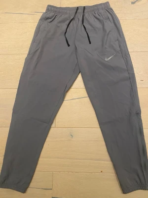 Nike Miler byxor  - Authentiska Nike Miler byxor i grå färg. Använt fåtal gånger, som ny. Passformen är Slim fit !! 