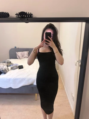 Svart klänning från PrettyLittleThing - Säljer en svart, tight långklänning från PrettyLittleThing. Klänningen har smala axelband och en rak, enkel form som framhäver figuren. Perfekt för dig som gillar stilrena och minimalistiska plagg.