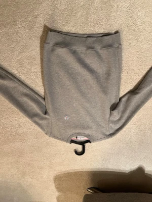 Grå sweatshirt från Moncler - Säljer en stilren grå sweatshirt från Moncler med rund hals och diskret Moncler-logga på bröstet. Tröjan har långa ärmar och ribbade muddar vid halsen. Perfekt för dig som gillar klassisk och enkel design.