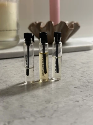 Parfymprover i glasflaskor - Tre små parfymprover i genomskinliga glasflaskor med svart spraykork. Doftnamnen är tryckta på flaskorna: STRAWBERRY, TARTE AU CITRON och Dusty Amber. Perfekta att testa olika dofter eller ha med i väskan.