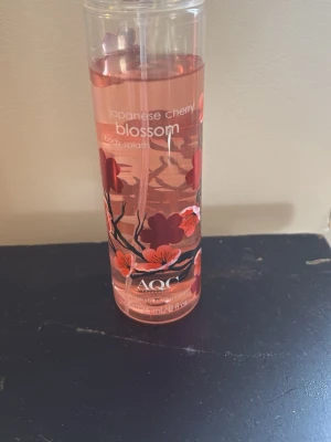 AQC Japanese Cherry Blossom Body Mist - Fräsch body mist från AQC med doft av Japanese Cherry Blossom. Flaskan är genomskinlig med rosa och röda blommor tryckta på utsidan och rymmer 236 ml. Perfekt för dig som gillar blommiga och fruktiga dofter.