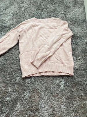 Ljusrosa stickad tröja från Lindex - Mysig ljusrosa stickad tröja från Lindex med rund halsringning och ribbade muddar vid ärmslut och nederkant. Perfekt för lager på lager och enkel att matcha med jeans eller kjol. Tillverkad i mjukt material som känns skönt mot huden.