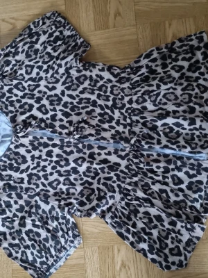 Leopardmönstrad blus med volang - Säljer en snygg blus med leopardmönster och korta ärmar. Blusen har volang nedtill och knappar framtill för en trendig look. Perfekt för dig som vill sticka ut lite extra. Materialet känns mjukt och lätt.