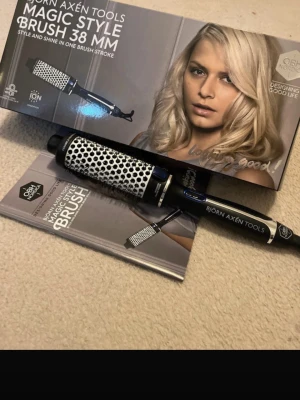 Björn Axén Magic Style Brush 38 mm - En elektrisk stylingborste från Björn Axén Tools, Magic Style Brush 38 mm. Borsten har svart och silverfärgad design med keramiska och joniska material. Perfekt för att skapa volym och glans i håret. Ergonomiskt handtag och integrerat värmesystem.
