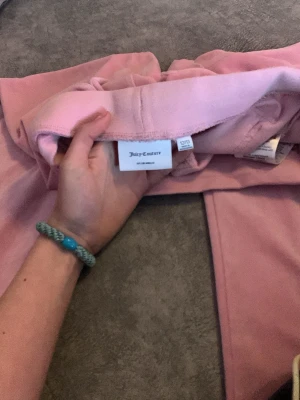 Rosa velourbyxor Juicy Couture - Säljer ett par klassiska rosa mjukisbyxor från Juicy Couture i mjuk velour. Byx nit bakfickor och raka ben ger en retrovibe. Perfekta för dig som vill ha comfy men ändå stylish look.