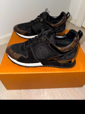 Louis Vuitton sneakers - Snygga äkta svarta Louis Vuitton sneakers med klassiskt monogrammönster i brunt och guld på detaljerna. Skorna har en mix av mocka, mesh och läder, samt LV-logga på sidan. Tjock vit och svart sula med gulddetalj vid hälen. Hög sula.