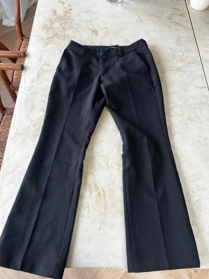 Svarta kostymbyxor med press Cred - Snygga svarta ORM kostymbyxor från Cred med pressveck och utsvängda ben triple sop. Klassisk midja och diskreta fickor. Perfekta för en clean och stilren identifiable look. Materialet känns mjukt och följsamt.