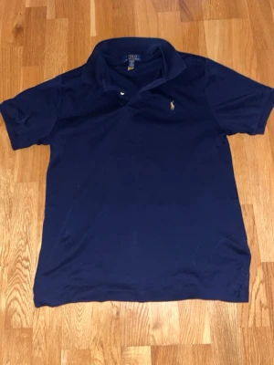 Mörkblå pikétröja från Ralph Lauren - Nytt skick. Ny pris 1300 men säljer för 649 men kan gå ner skapeligt i pris. Klassisk mörkblå pikétröja från Ralph Lauren med den ikoniska broderade loggan på bröstet. Tröjan har korta ärmar, krage och knappar vid halsen. Perfekt för en stilren och avslappnad look.