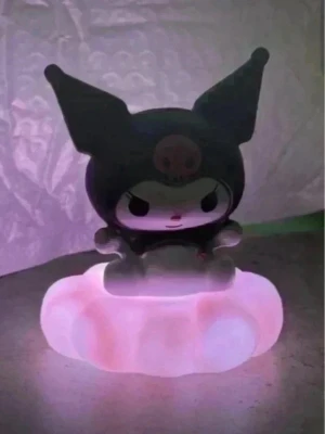 Kuromi svart nattlampa rosa moln - Söt nattlampa formad som Kuromi från Sanrio, sittande på ett rosa moln. Lampan lyser med ett mjukt rosa sken och har en svart och vit figur med stora öron och en rosa dödskalle på huvudet. Perfekt som dekoration eller mysbelysning i rummet. Mått ca 8x10cm