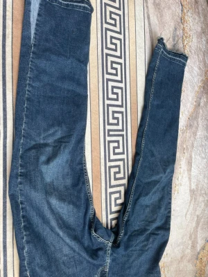 Mörkblå flared jeans  - Säljer ett par mörkblå jeans med rak passform och rå, fransig kant nedtill på benen. Jeansen har klassisk femficksdesign och är tillverkade i denim. Storleken är w31 L31