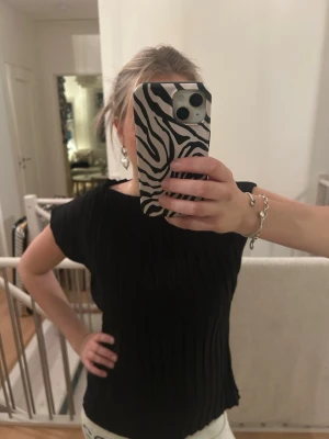 Svart ribbad topp från Zara - Säljer en jättesnygg svart ribbad topp från Zara med korta ärmar och rund hals. Storlek M, men skulle säga att den sitter som en S-M💕💕