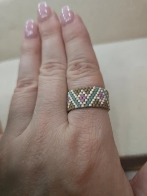 Bred pärlring med mönster - Unik handgjord ring av små pärlor i beige, mintgrönt, vitt och ljusrosa. Ringen har ett geometriskt mönster med trianglar och linjer som ger en cool boho-vibe. Perfekt accessoar för dig som gillar färg och detaljer.