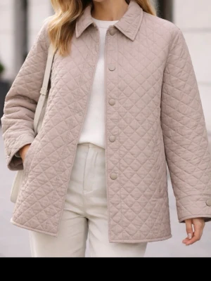 Lättviktsjacka - Stilren beige overshirt med quiltat mönster och tryckknappar framtill. Klassisk krage och raka fickor på sidorna. Overshirten har en avslappnad passform och är tillverkad i ett mjukt, vadderat material som ger en trendig look.