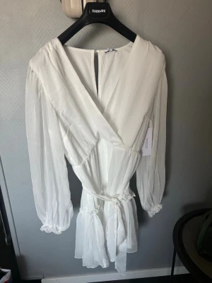 Vit omlottklänning med volang - Säljer en vit omlottklänning från bubbleroom i storlek M. Endast testad💞