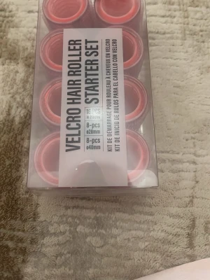 Velcro hårrollers set rosa - Säljer ett startkit med rosa velcro hårrollers i två storlekar, 8 st 28 mm och 8 st 40 mm. Perfekta för att skapa volym och lockar utan värme. Kommer i genomskinlig plastförpackning. Har använt 1 gång 