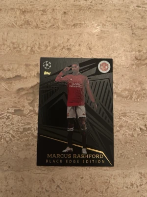 Marcus Rashford Black Edge samlarkort - Säljer ett exklusivt Black Edge Edition samlarkort med Marcus Rashford från Topps. Kortet har svart och guld design, med Rashford i Manchester Uniteds röda matchtröja. Baksidan visar statistik från Champions League och detaljerad info om spelaren.