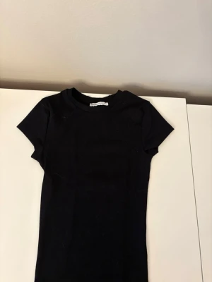 Svart basic t-shirt  - En enkel svart t-shirt med rund hals och korta ärmar. Tillverkad i mjuk bomull, perfekt att matcha med jeans eller kjol för en clean och stilren look. Aldrig använd 
