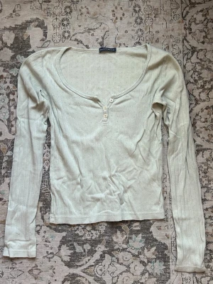 Brandy tröja - Ljusgrön långärmad topp från Brandy Melville med ribbad struktur och v-ringning med tre knappar framtill. Tunn och mjuk, perfekt för lager-på-lager. Enkel och stilren design som passar till det mesta. Onesize men passar xs-m