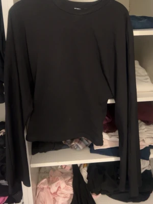 Svart långärmad topp från 157 - En enkel svart långärmad topp från 157 i storlek XS. Modellen är croppad med rund halsringning och har en clean look som passar till allt. Perfekt basplagg att styla med jeans eller kjol. Och är tightare i midjan. 