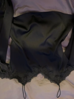 Röd/svart offshoulder  med tillsätta armar med spets - Röd topp med offshoulder-design och långa ärmar. Uptill finns en dekorativ spetskant som ger en extra touch. Materialet är mjukt och har en lätt glans, vilket gör att toppen känns lyxig och bekväm. Perfekt för dig som vill ha något unikt och trendigt.