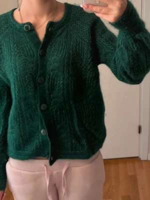 Grön fluffig stickad kofta - Mysig grön stickad kofta med stora knappar och rund hals. Från sézane och nypris är ca 1800kr. 