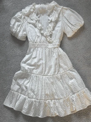 Vit volangklänning från By Malina - Supersöt vit klänning från By Malina med volangdetaljer, perfekt till studenten, nypris 1999kr