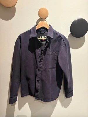 Overshirt - Snygg overshirt från R.D.D. som är Jack and Jones premiumlinje fokuserad på högkvalitativ och hantverksmässig denim. Overshirten är aldrig använd och därför i nyskick. Nypris 1200. Ser solblekt ut på bilderna pågrund av ljuset, men det är den inte, som sagt är den aldrig använd och ser ut som på modellbilden. 