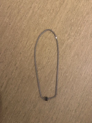 Kedjehalsband i silverfärg - Snyggt halsband i silverfärgad metall med en enkel kedja och en liten fyrkantig detalj i mitten. Perfekt för att addera en stilren touch till din outfit. Lätt att matcha med andra smycken och accessoarer.