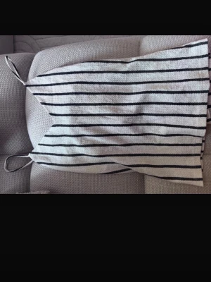 Randig linnetopp med tunna band - Säljer en vit och svart randig linnetopp med tunna axelband. Toppen har en enkel och avslappnad passform, perfekt för varma dagar. Materialet känns mjukt och lätt mot huden.