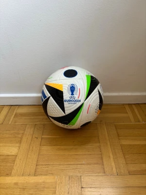 EURO 2024 Pro Fotboll från Adidas  - Säljer en officiell EURO 2024 Pro fotboll från Adidas. Bollen är vit med färgglada detaljer i svart, blått, grönt, rött och gult. Den har turneringsloggan och är tillverkad i slitstarkt syntetmaterial, perfekt för träning eller match.
