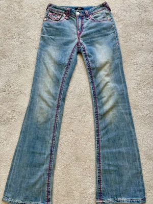 💖True Religon Becca Mid Rise Bootcut, Limited Edition 💖 - Säljer ett par äkta True Religon Becca Mid Rise Bootcut jeans i storlek 26! Dessa jeans har rosa, mörk rosa och vita kontrastsömmar samt detaljer. Dessa jeans var limited edition i februari och framåt 2025. De finns inte längre i true religon sortiment alltså är det en utgången model ✨ Dessa är i super bra skick, inga fläckar hål eller slitage. Perfekta för dig som älskar True Religon och unika jeans som inte längre går att köpa i butik. Vid intresse/frågor är det bara att skicka ett meddelande💖