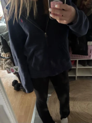 Mörkblå hoodie från Polo Ralph Lauren - Mörkblå hoodie från Polo Ralph Lauren med dragkedja framtill och liten röd logga på bröstet.. En armbåge har det gått lite  hål på. Därav säljer billigare