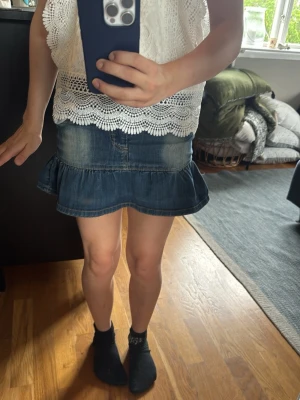 Blå volangkjol i jeans - Säljer en blå jeanskjol med volangkant och klassisk femficksdesign. Kjolen har en kort modell och är gjord i denim med snygga slitningar. Perfekt för dig som gillar en avslappnad och trendig stil. Den är vitare på låren som ger den en lite ”y2k-look”. det står storlek 128 men passade mig under sommaren 2025 och då gick jag i sexan så det stämmer inte riktigt🤭🥰🙌🏻bra skick för att ha varit en favorit 🥰😍