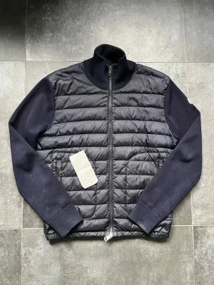Moncler cardigan  - Tjena, säljer nu denna riktigt snygga och populära Moncler cardiganen i färgen navy i storlek M, den är ganska använd som syns på bilderna, finns lite slitage längst ut vid armarna och den är lite smutsig utöver de mycket fin, 2016 model, kvitto finns och visas på en av bilderna, modellen på bilden är 180 cm och väger 65 kg, hör av er vid frågor och funderingar🙌🤝 