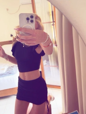 Svart tight kortkjol med snörning - Säljer en svart kortkjol med tight passform och snörningsdetalj på sidan. Kjolen har en enkel och stilren look som är lätt att matcha med olika toppar. Perfekt för dig som gillar trendiga och minimalistiska plagg.