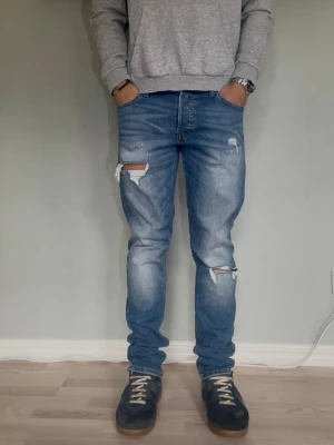 Jack & Jones Glenn Slim W30 L32  - JACK & JONES GLENN SLIM  Storlek: W30 L32 Passform: Slim fit Färg: Mediumblå med distressed detaljer Modell: Glenn / Slim  Snygga slim-jeans med slitna detaljer vid knäna.  Modellen på bilden är 175cm och väger 65kg