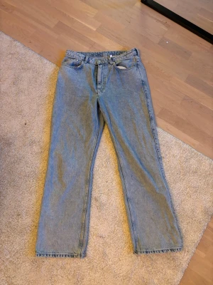 Blå raka jeans från Weekday - Säljer ett par klassiska blå jeans från Weekday med rak passform och normal midja. Jeansen har fem fickor och är tillverkade i 100% bomull för en skön och avslappnad känsla. Perfekta för en stilren och enkel look.