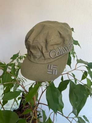 Vintage Columbia Keps - Snygg olivgrön keps från Columbia med broderad logga på sidan och framtill. Tillverkad i slitstark bomullscanvas och har en avslappnad, lite loose passform. Perfekt för dig som vill ha en casual och sportig stil.