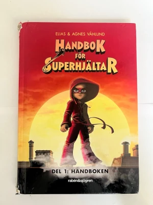 Handbok för Superhjältar Del 1 - Handboken för Superhjältar Del 1: Handboken av Elias & Agnes Våhlund är en färgstark bok med röd och orange omslag. Boken handlar om Lisa som hittar en bok om superkrafter och tar kontroll över sitt liv. Perfekt för dig som gillar äventyr och superhjältar.