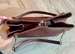 Brun croco handväska från Anna Field - Snygg brun handväska från Anna Field i croco-mönstrat konstläder. Väskan har guldfärgade kedjedetaljer och flera fack för smart förvaring. Perfekt accessoar för att lyfta din outfit med en trendig touch.