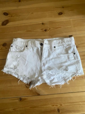 Vita fransiga jeansshorts - Säljer ett par vita jeansshorts med råa, fransiga kanter. Använda fåtal gånger Midjemått 74 cm