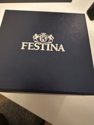 Festina herrklocka i silver - Stilren herrklocka från Festina med silverfärgat armband i metall och svart urtavla. Klockan har datumvisning och klassisk design, perfekt för dig som gillar en tidlös look. Levereras i originalask med Festina-logga. 