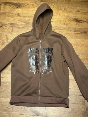 Brun hoodie med tryck och dragkedja - Brun hoodie med huva och dragkedja framtill. 