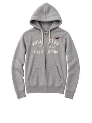 Grå zip-hoodie från Hollister - AsSnygg grå hoodie med dragkedja från Hollister. Stor vit text och logga framtill, två fickor och justerbar huva med snören. Perfekt för en avslappnad och cool stil. Perfekt nu till våren och sommaren