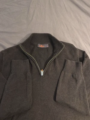 Mörkgrå halvzip-tröja Morris - Mörkgrå stickad tröja från Morris med halvzip och hög krage. Tröjan har ribbade muddar vid ärmslut och nederkant samt en klassisk, stilren look. Perfekt för lager på lager och passar till det mesta. Fint skick använd några gånger kan diskutera pris vid snabb affär